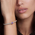Close-up of a woman wearing the Signature Caviar Two-Tone Amethyst Oval Mini Versa Torque Bracelet, featuring sterling silver caviar beading, 14K gold accents, and a purple gemstone.