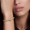 Signature Caviar Two-Tone Peridot Oval Mini Versa Torque Bracelet on wrist, showcasing sterling silver caviar beading and 14K gold accents, with a vibrant green peridot centerpiece.
