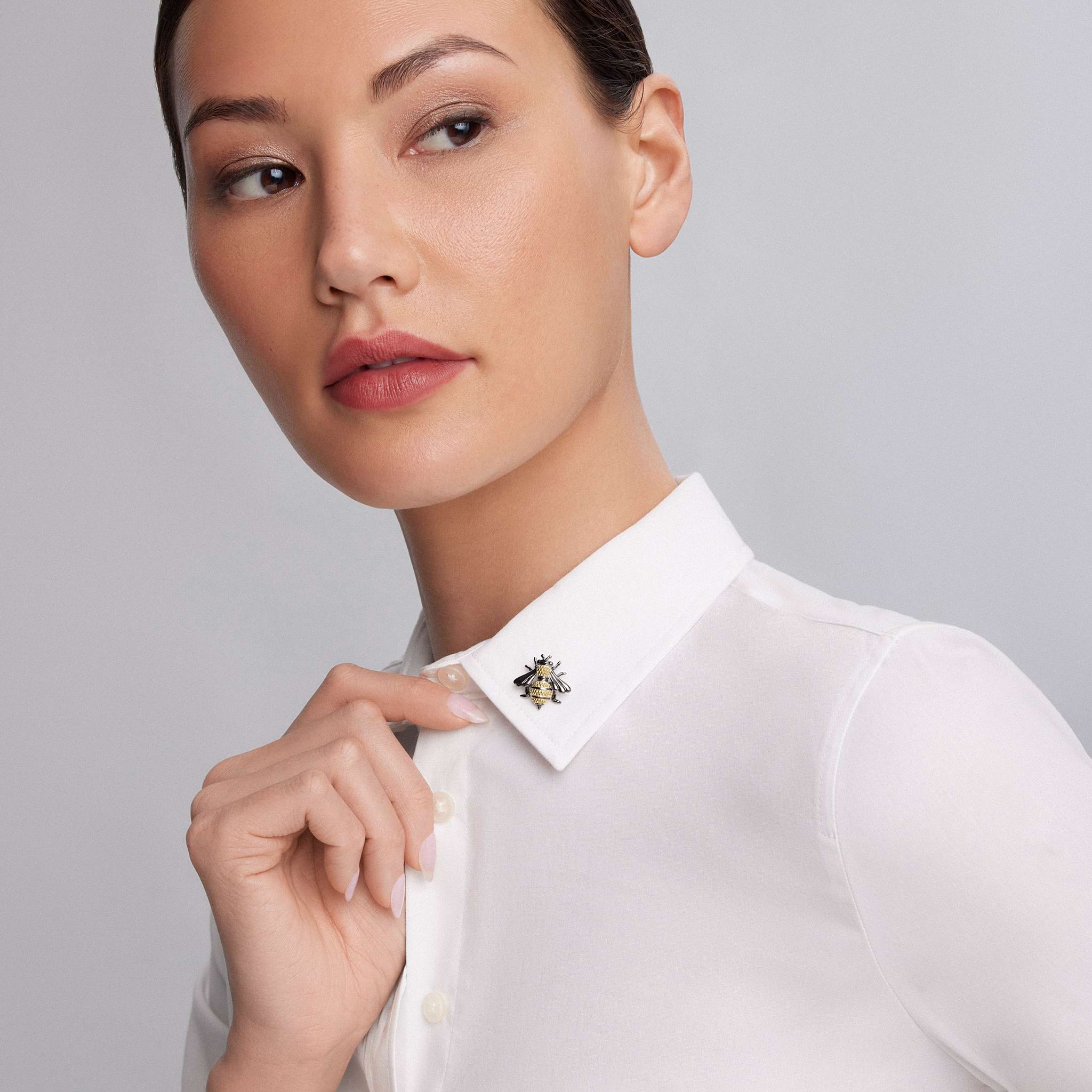 A person wears a crisp white shirt with the Rare Wonders Large Honeybee Pin, featuring 18K gold Caviar beading and black rhodium accents on sterling silver.
