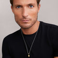 Man wearing Anthem 18K Gold Caviar Beaded Skull Amulet featuring intricate Caviar beading, dimensions 14mm x 9mm