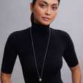 Hearts of LAGOS Silver Heart of Philadelphia Pendant Necklace shown on a model wearing a black turtleneck, featuring a detailed sterling silver heart pendant with cultural icons.