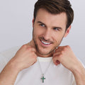 Man wearing Sterling Silver and Emerald Cross Amulet featuring smooth sterling silver with emerald accents