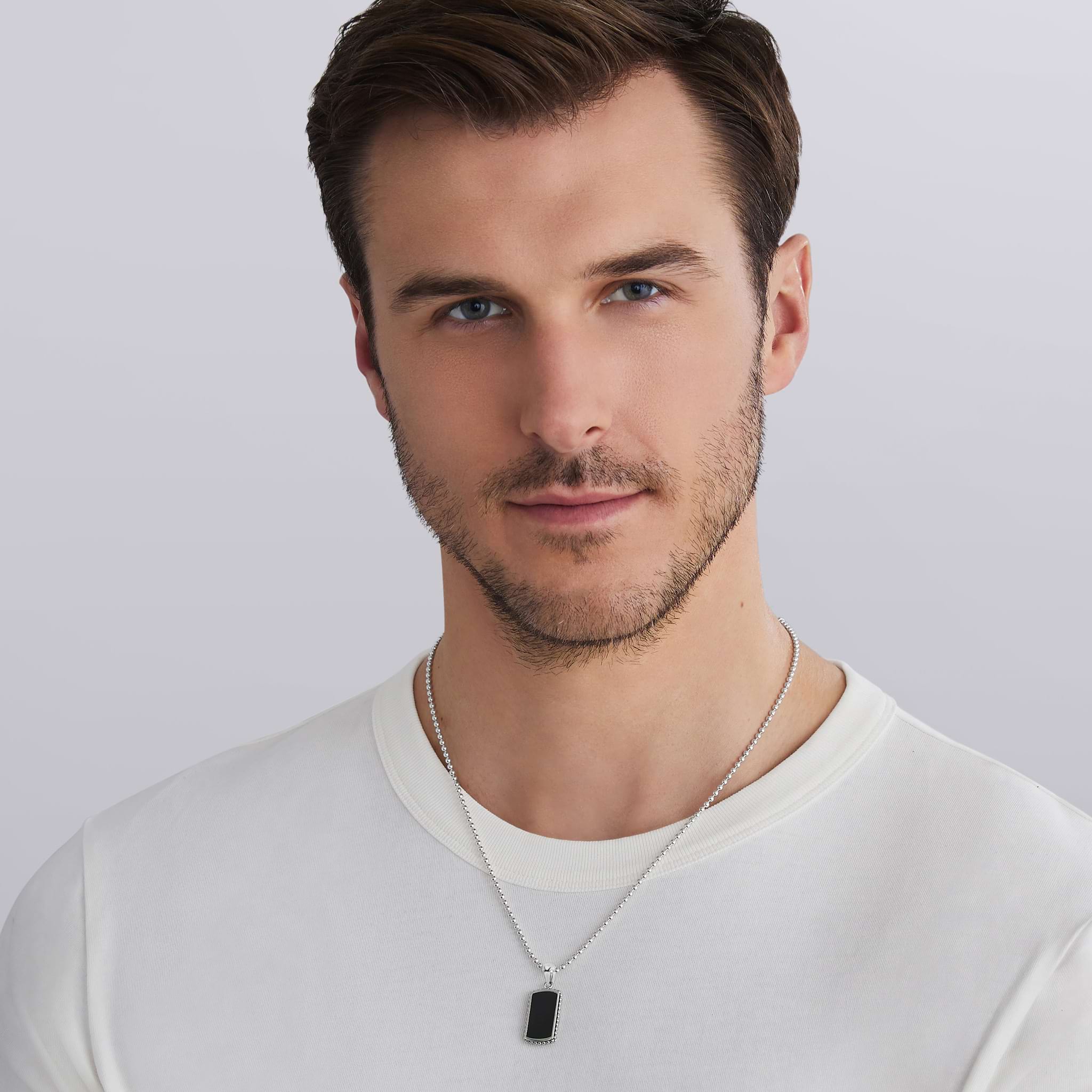 man wearing sterling silver tag amulet with black agate and Caviar beading, 34 × 14 mm