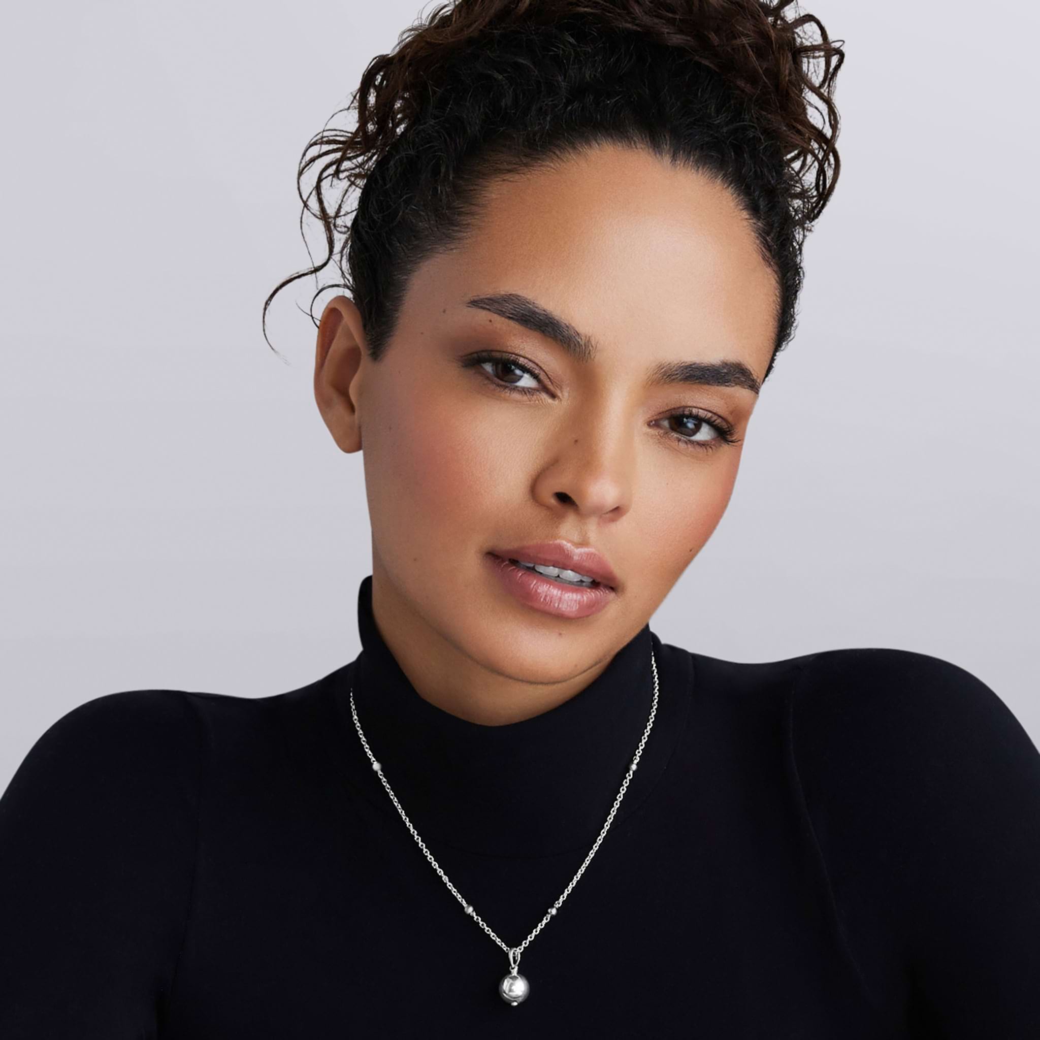 Woman wearing a short chain necklace with a sterling silver bead pendant