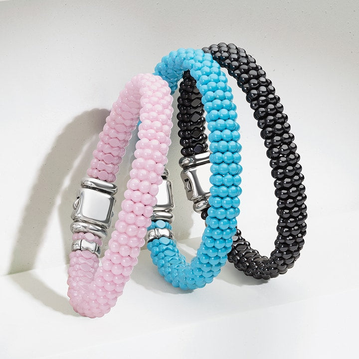 Three beaded bracelets in pink, blue, and black on a light gray background