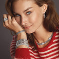 Woman wearing Caviar Spark Beaded Diamond Hoop Earrings with sterling silver and caviar beading, complemented by matching silver jewelry, highlighting elegance and modern design.