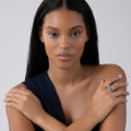 Person with crossed arms wearing Rittenhouse Bezel-Set Swiss Blue Topaz Ring, featuring a large blue gemstone and 18K Caviar beading on a sterling silver band.