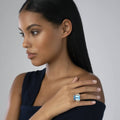 A young woman wearing the Glacier Large Emerald-Cut Swiss Blue Topaz Ring in sterling silver with 18K gold caviar beading by LAGOS.