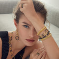 Woman wearing the Meridian 18K Gold and Black Ceramic Link Bracelet, with stacked bracelets, rings, matching chain-link necklace, and drop earrings, highlighting layered textures.