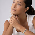 Woman wearing the Signature Caviar Blue Sapphire Caviar Bracelet, featuring silver beads with gold accents and a blue sapphire pavé station, resting hand on cheek.