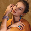 Model wearing a stack of gemstone bangle bracelets