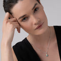 Woman wearing a simple black top showcases the Rare Wonders Turquoise Beetle Diamond Pendant Necklace featuring turquoise, diamond accents, and a silver chain.
